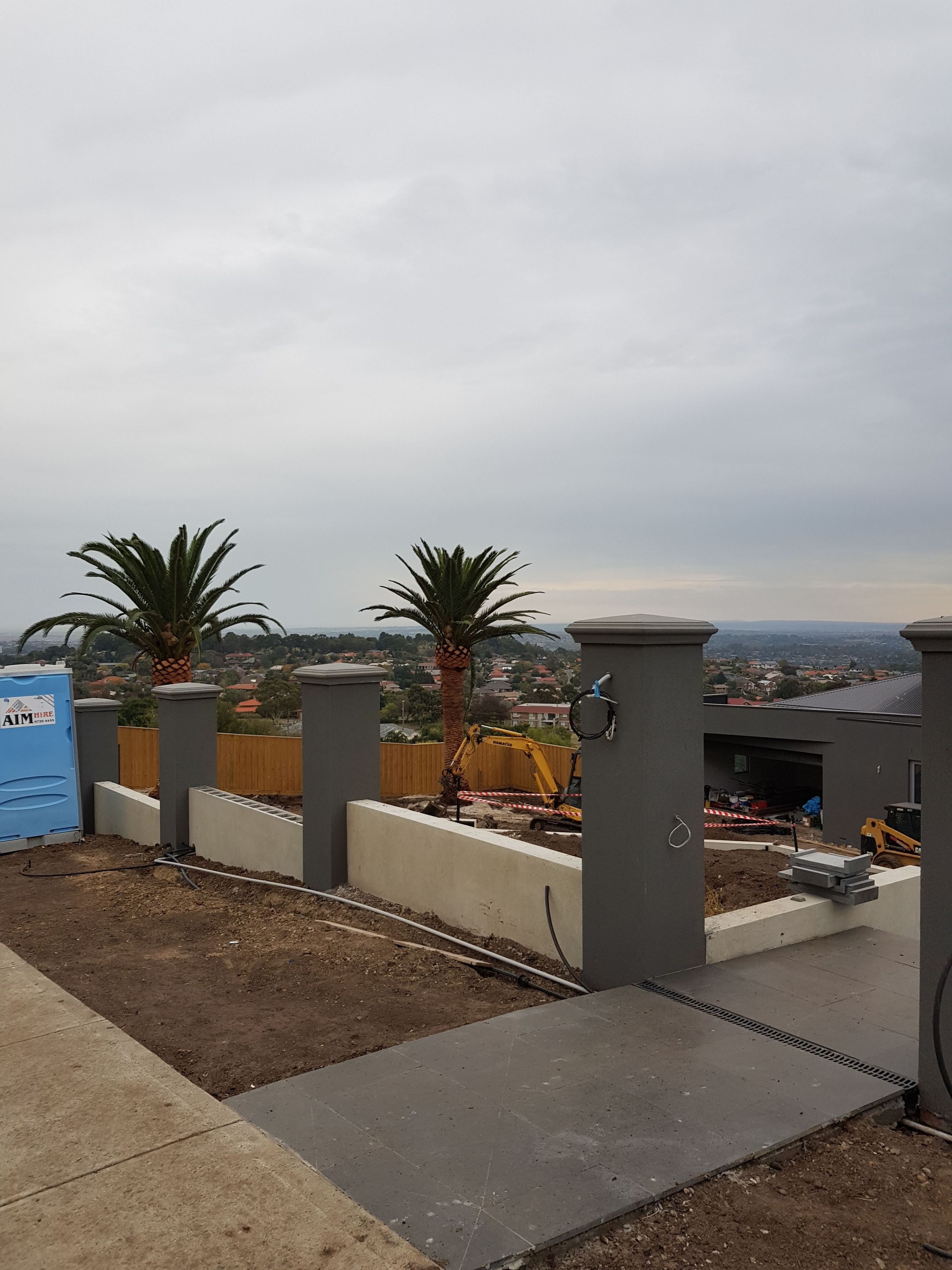 Full length concrete sleeper retaining wall holding a cut level above a lawn