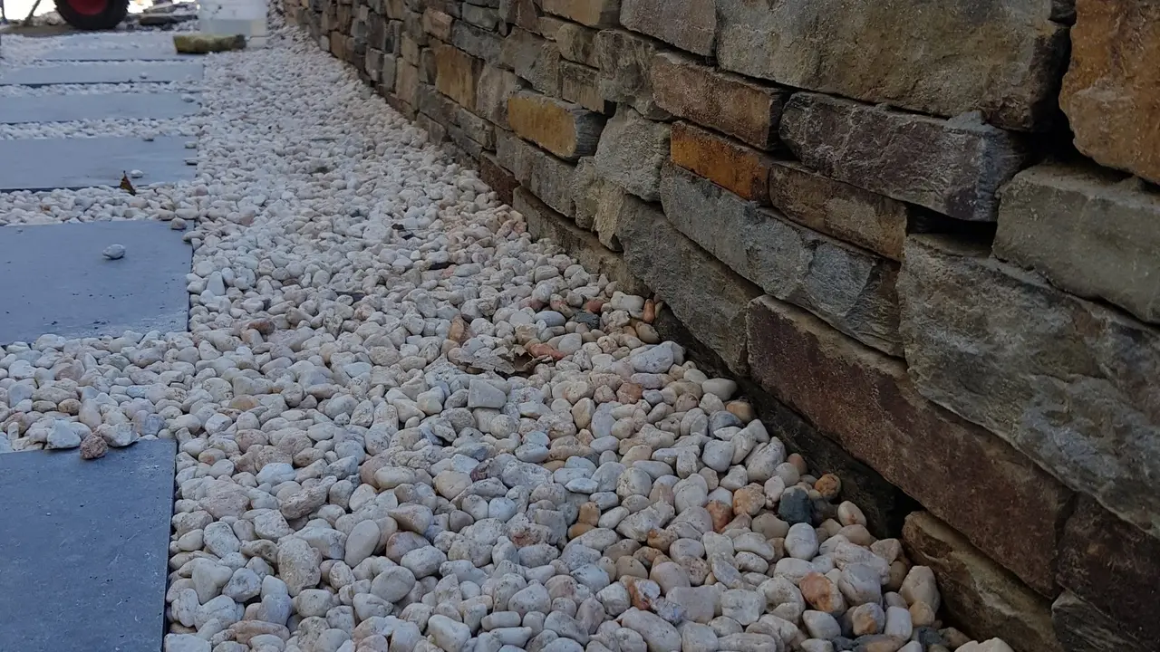 Curved rock retaining wall and pebble path